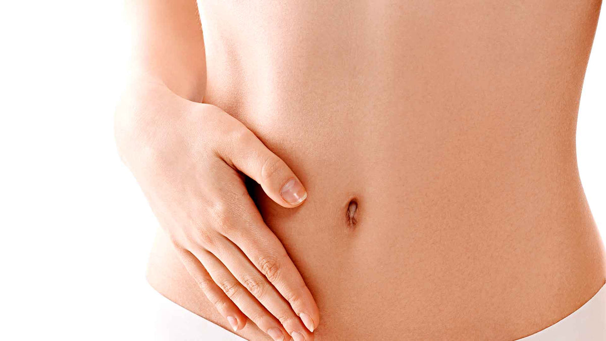 Eine Frau mit nacktem Oberkörper hält sich die rechte Hand auf ihren Bauch, um Verdauungsprobleme anzudeuten.