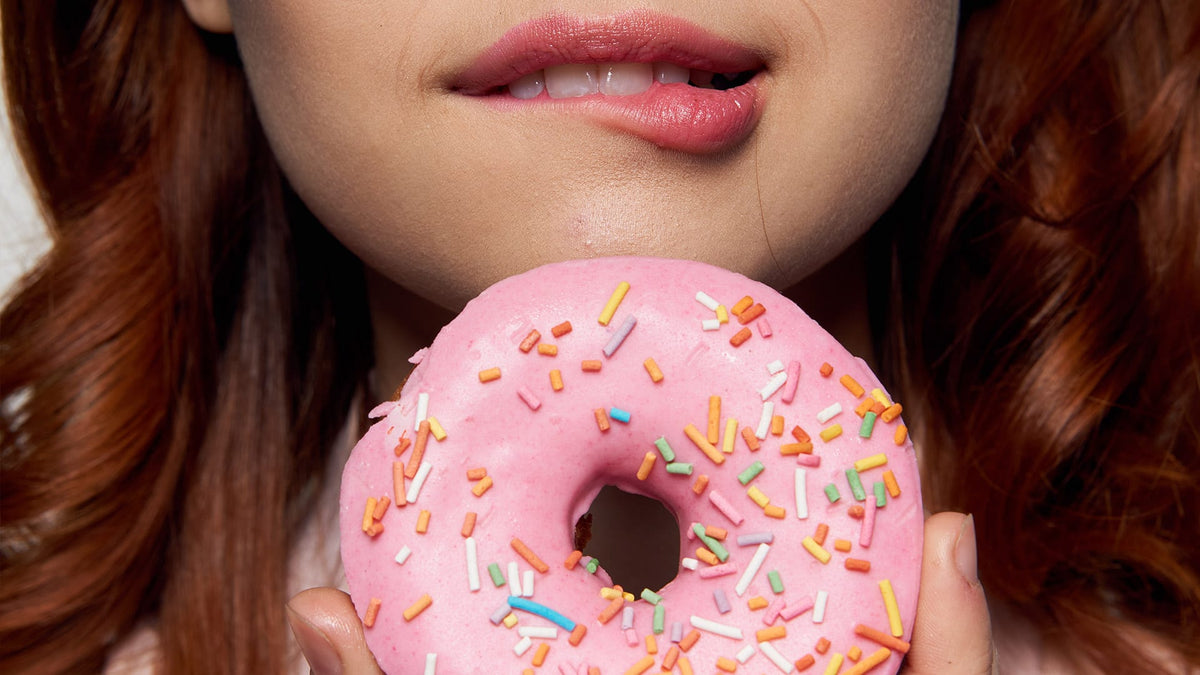 Nahaufnahme von einer Rothaarigen wie sie kurz davor ist in einen Donut zu beißen