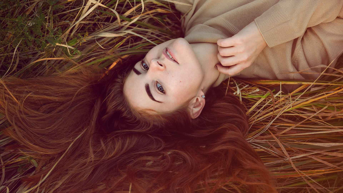 Eine junge Frau liegt auf einer Wiese. Ihre schönen langen Haare sind auf Wiese ausgebreitet