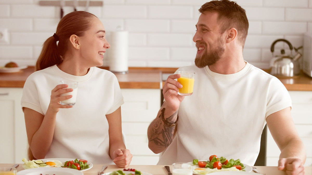 Ein junges Päarchen sitzt in der Küche und ernährt sich mit gesundem Essen.
