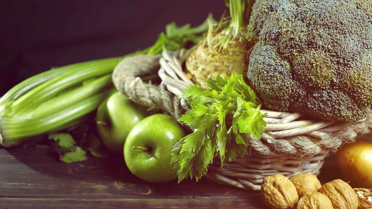 Zusammenstellung von grünen Gemüse wie Staudensellerie, Brokkoli, grünen Äpfeln und Walnüssen
