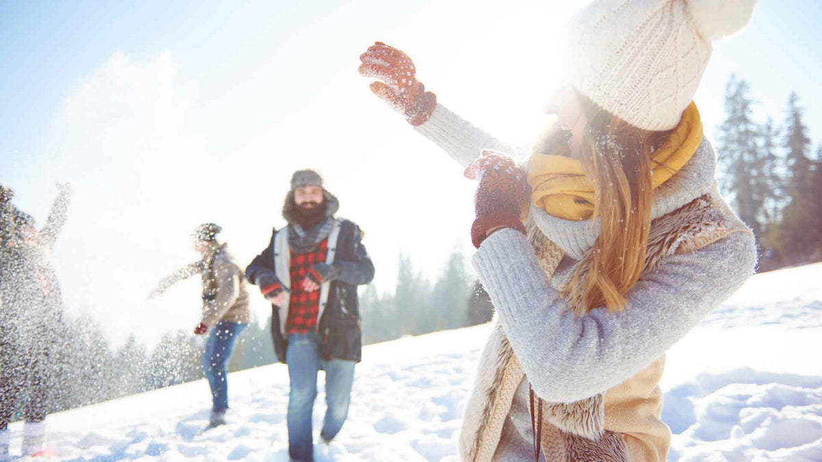 Junge Leute in einer Schneelandschaft bei einer Schneeballschlacht.