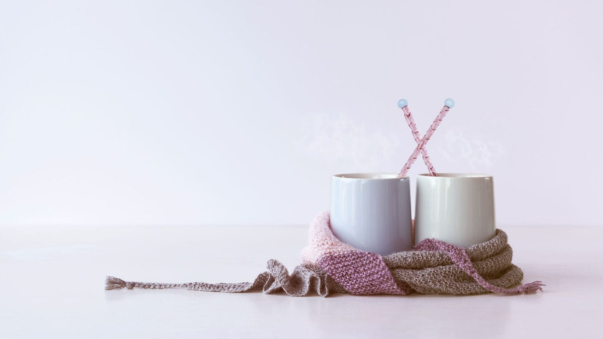 Ein Wollschal ist um zwei Tassen gewickelt