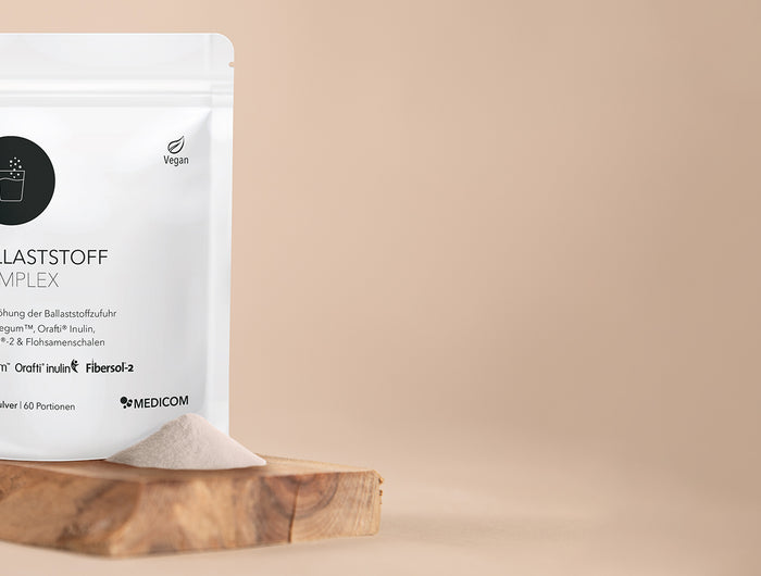 Die Packung von Ballaststoff Complex auf einem Holztablett mit einem Haufen Ballaststoffpulver davor