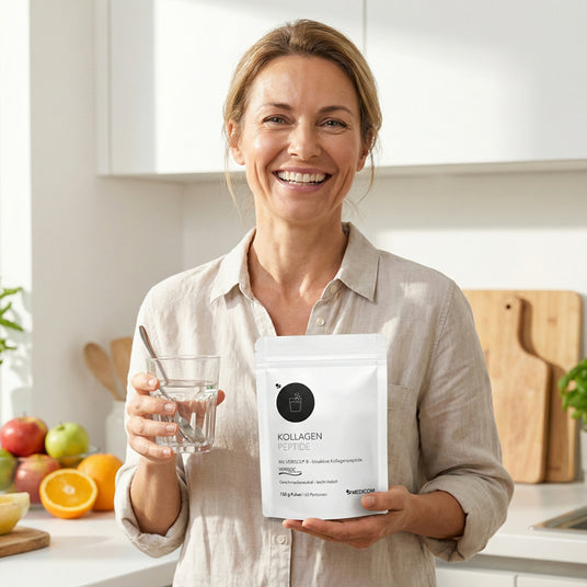 Lächelnde Frau in einer Küche mit einem Glas Wasser und einer Tüte mit der Aufschrift "Kollagen Peptide".