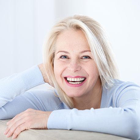 Eine Frau mittleren Alters in den Wechseljahren lacht in die Kamera