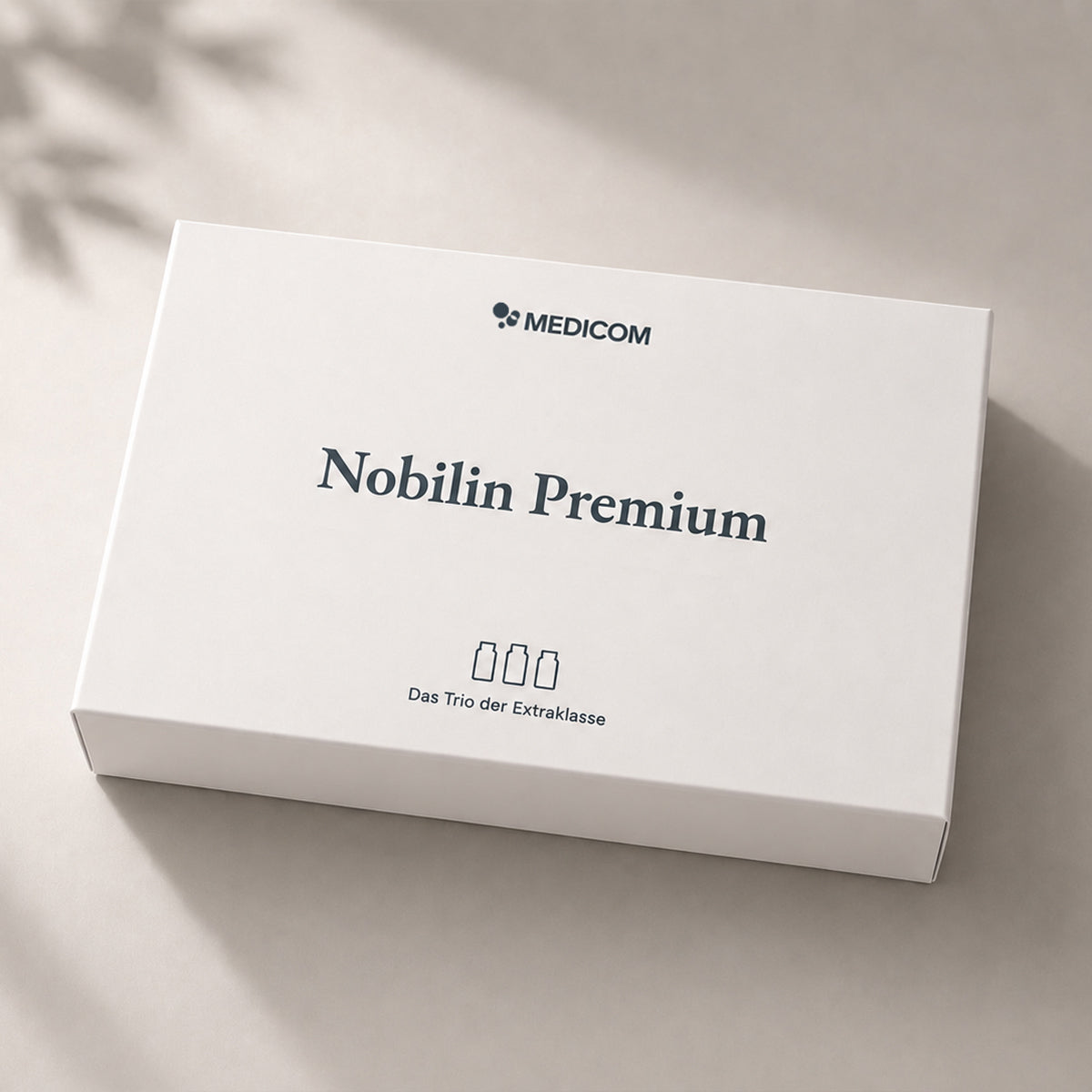 Die neue, wiederverwendbare Medicom-Box: Rechteckige Nobilin Premium-Produktverpackung mit einem Symbol, das drei Flaschen darstellt. Das Trio der Extraklasse