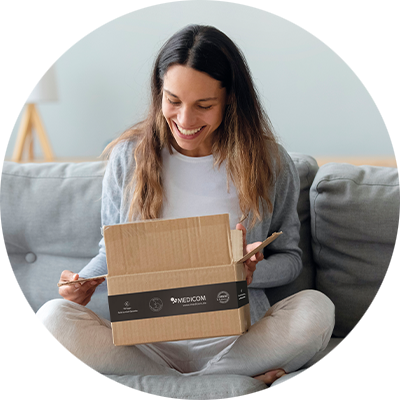 Eine Frau öffnet ihr Medicom-Bestellpaket und freut sich.
