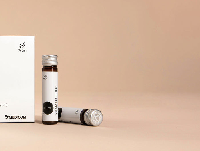 Die Packung von Vitamin C Shot 1.000 mg und zwei Trinkampullen links im Bild