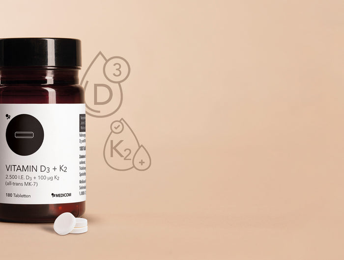 Die Produktdose von Vitamin D3+K2 von Medicom links im Bild und drei Tabletten davor
