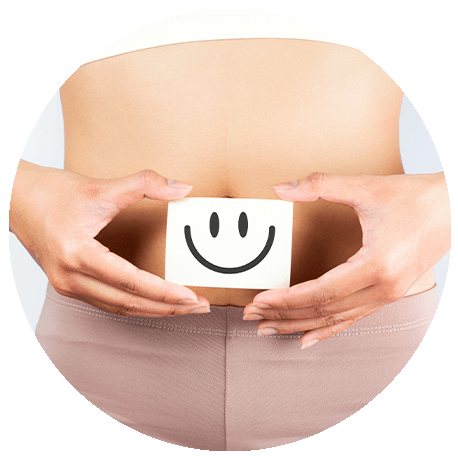 Ansicht eines weiblichen Oberkörpers. Frauenhände halten einen Smiley vor dem Bauchnabel