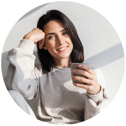 Junge Frau in bequemer Kleidung mit Tasse entspannt an Wand angelehnt