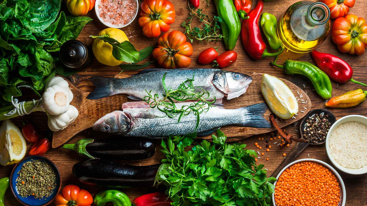 Zwei Fische, Obst und Gemüse auf einem Holzhintergrund schön hergerichtet