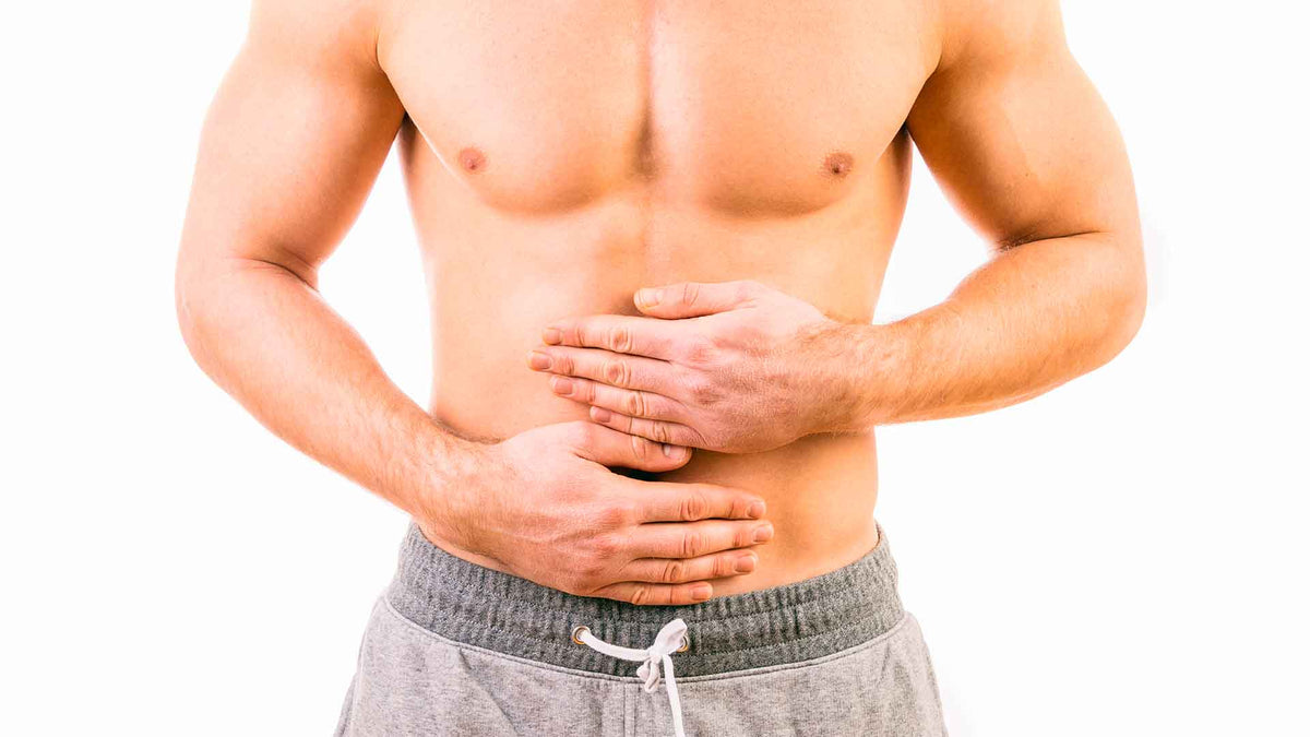 Ein junger Mann mit muskulösem, nackten Oberkörper hält sich die Hände auf den Bauch