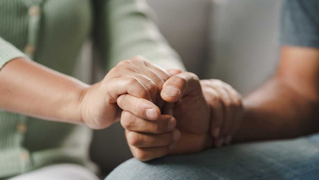 Eine Hand hält stärkend eine andere Hand.