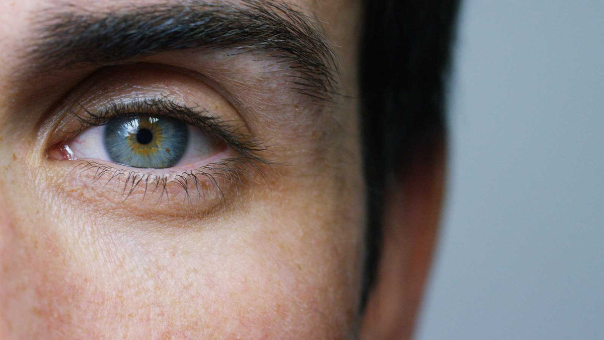 Nachaufnahme eines männlichen Gesichts. Das linke Auge eines Mannes mit blau-gelben Augen.
