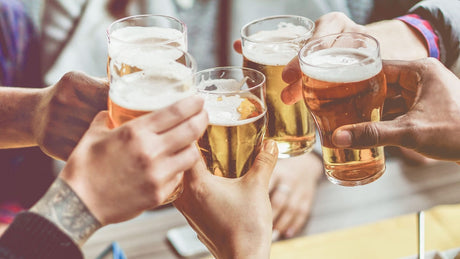 In einer Gruppe wird mit Biergläsern angestoßen.