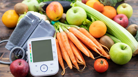 Gemüse und Obst und ein Bluthochdruckmesser auf einer dunklen Fläche