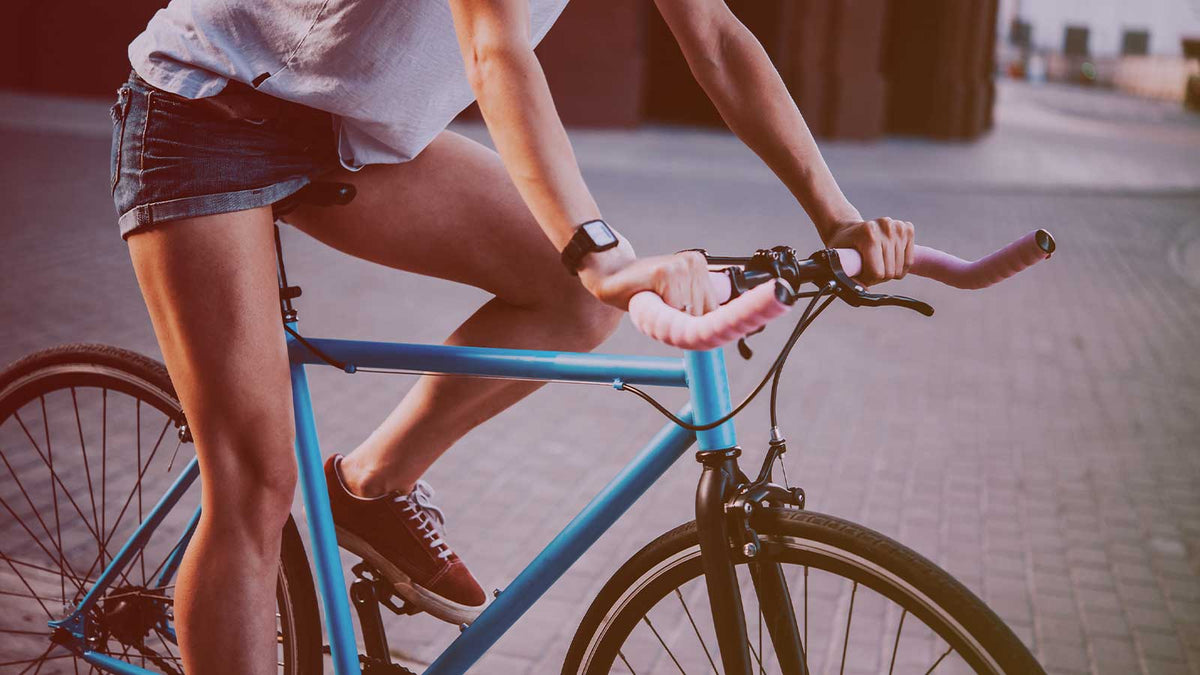 Ein junge Frau in kurzer Jeanshose fährt auf einem Fixiefahrrad