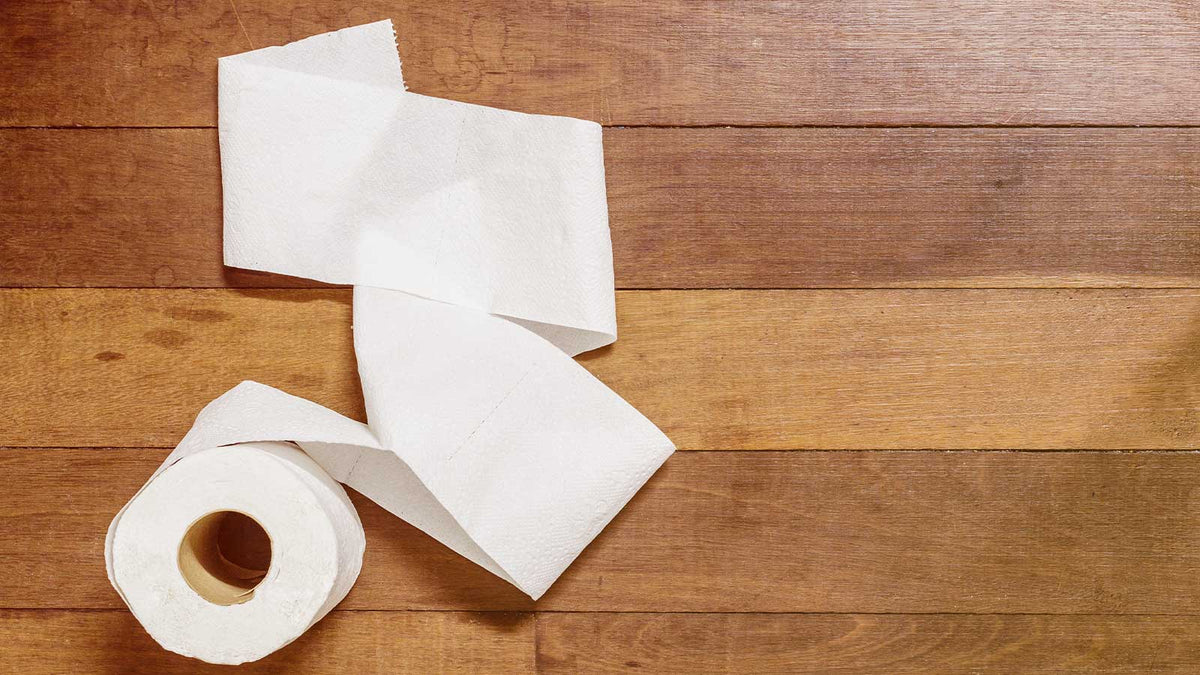 Auf dem Parkettboden liegt eine Toilettenpapierrolle