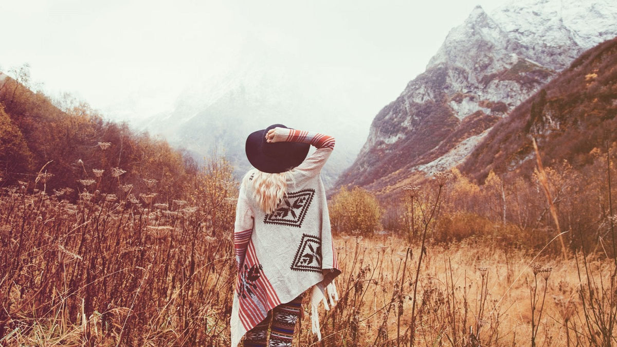 Eine Frau steht vor einer Berglandschaft. Es ist neblig und kalt.
