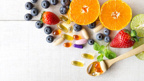 Orangen, Beeren und Vitaminkapseln stilvoll präsentiert auf weißem Untergrund
