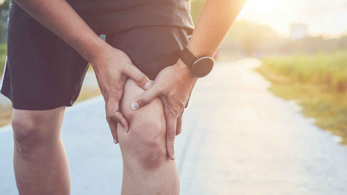 Ein Mann in Sportbekleidung fasst sich an sein linkes Knie