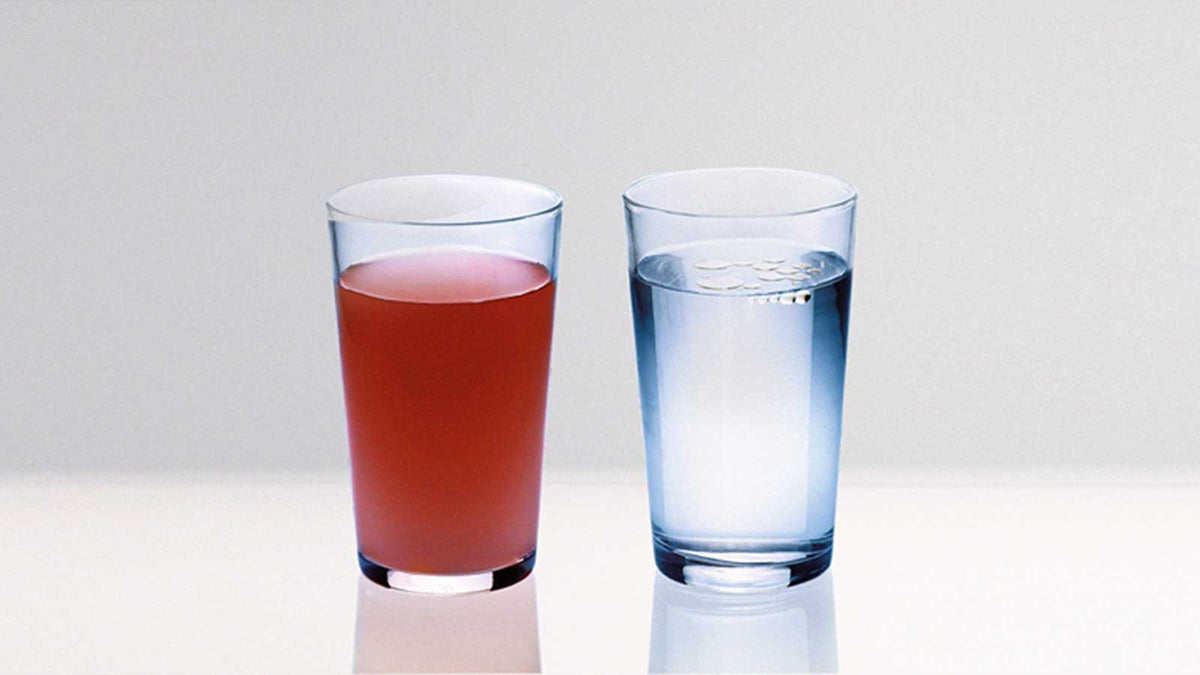 Zwei Wassergläser. Links im Bild Krillöl mit Wasser vermischt. Rechts im Bild Fischöl schwimmt auf der Oberfläche des Wasserglases.