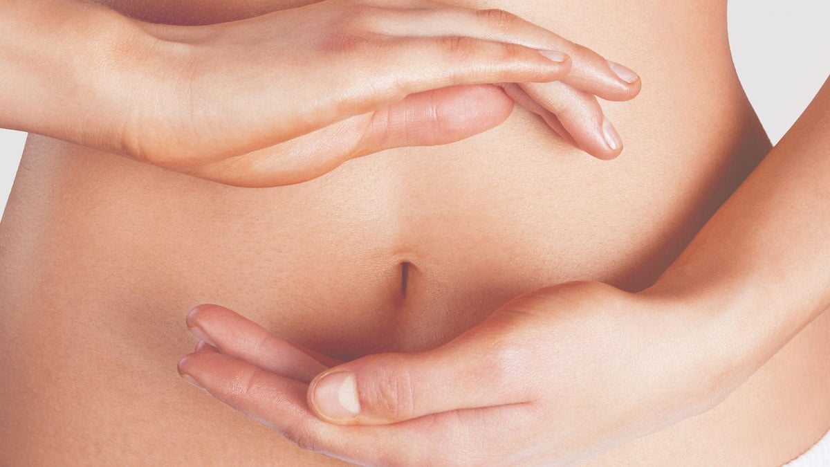 Frauenhände formen vor einem nackten Bauch einen ovalförmigen Kreis.