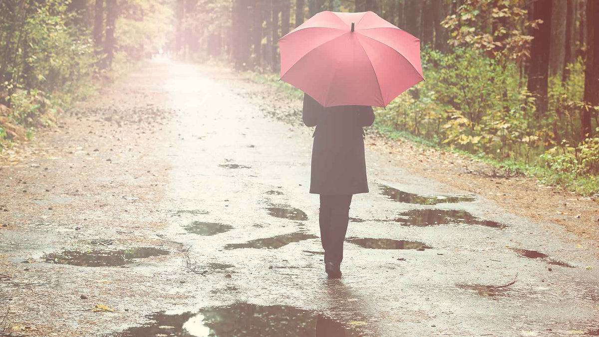 Ein Frau mit rotem Regenschirm geht im Regen spazieren
