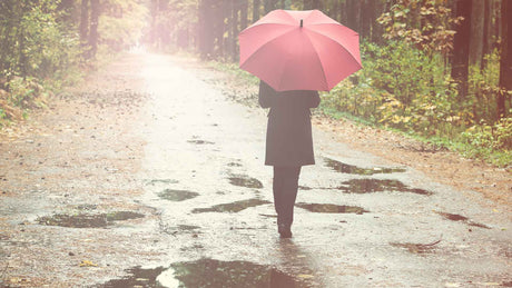 Ein Frau mit rotem Regenschirm geht im Regen spazieren