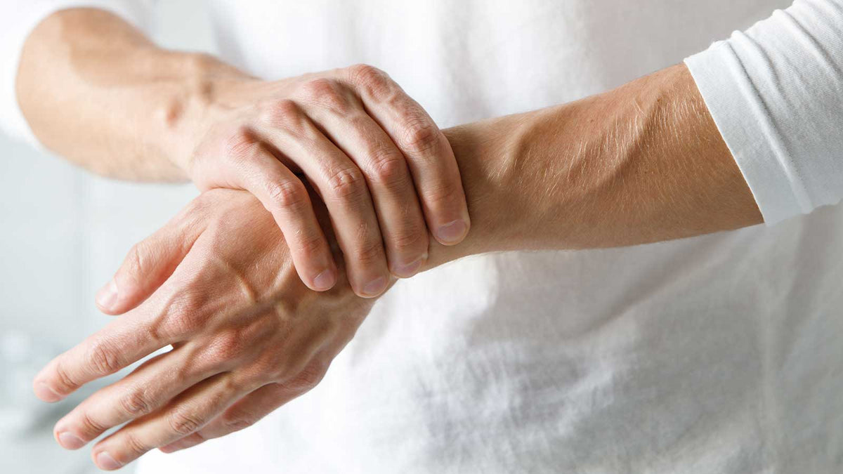 Ein Mann hält sich das Handgelenk.