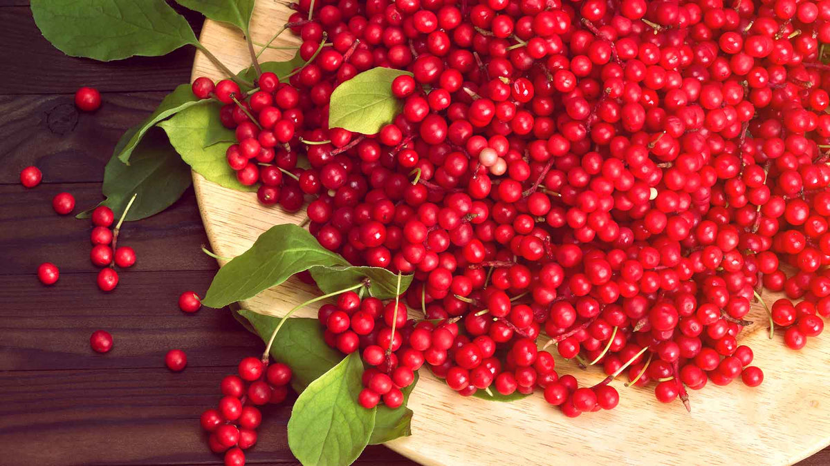 Schisandrabeeren und Schisandrablätter auf einem runden Holztablett präsentiert