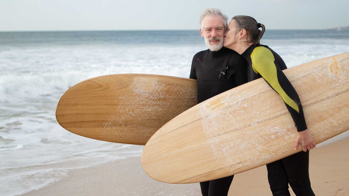 Zwei Surfer im Neoprenanzug und Surfbrettern am Strand