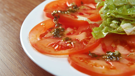 Fein geschnittene Tomaten mit Balsamico-Essig und Salatblättern. Tomaten-Carpaccio