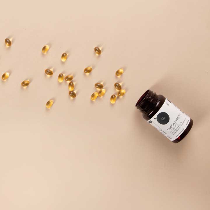 Die Produktdose von Omega 3 Vegan Algenöl geöffnet. Kapseln sind auf dem Bild verteilt