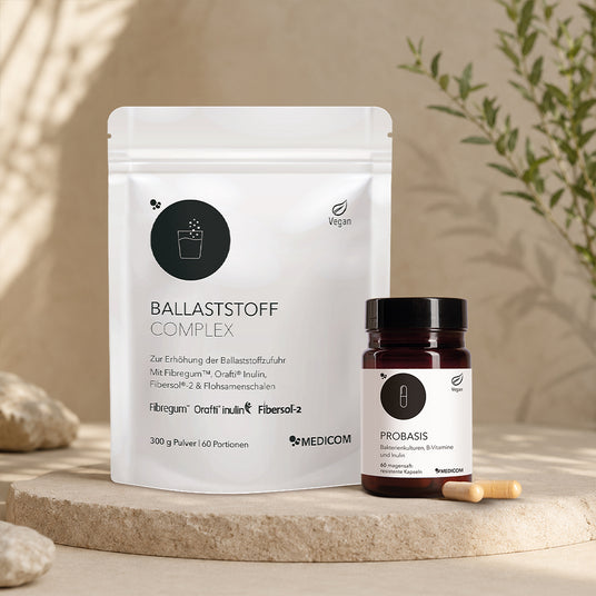 Die Produktdose von ProBasis von Medicom mit zwei Kapseln im Vordergrund (rechts im Bild) und der Beutel von Ballaststoff Complex (Links im Bild).