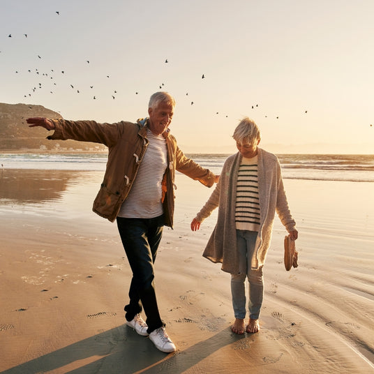 Ein älteres Paar geht am Strand spazieren und haben Spass zusammen. Das Bild ist für die Black Friday Aktion 2025 von Medicom