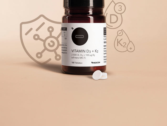 Die Produktdose von Vitamin D3 + K2 Tabletten und drei Tabletten im Vordergrund