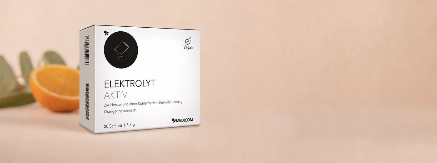 Die Faltschachtel von Elektrolyt Aktiv in der Frontansicht. Im Hintergrund eine halbe Orangenschale.