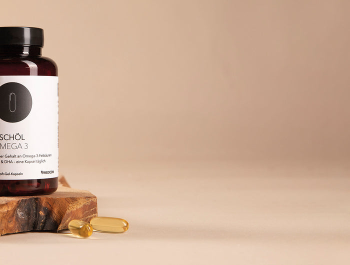 Die Dose von Fischöl Omega 3 von Medicom auf einer Holzunterlage und zwei Fischölkapseln davor