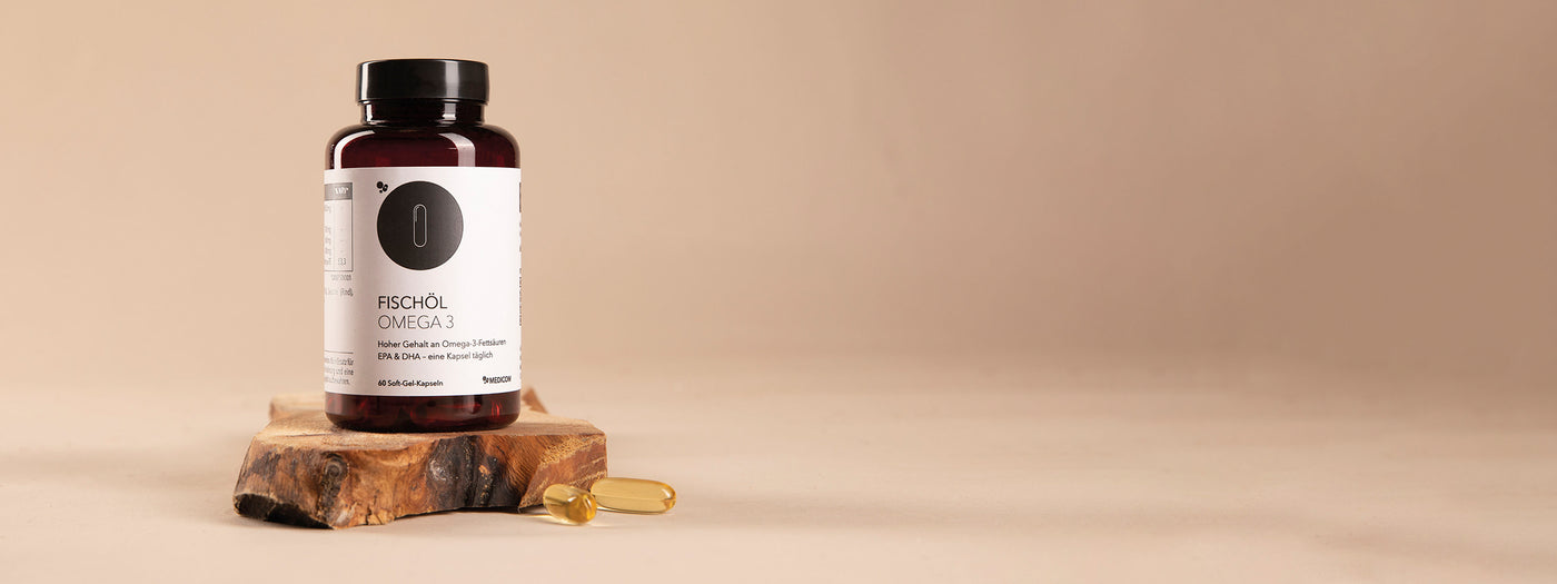 Die Dose von Fischöl Omega 3 von Medicom auf einer Holzunterlage und zwei Fischölkapseln davor