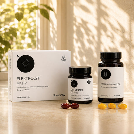 Drei Produkte von Medicom, die das Medicom GLP-1 Begleitset Energie & Nährstoffdichte ausmachen: QH Mono 50 mg, Vitamin-B-Komplex und Elektrolyt Aktiv. Die drei Produkte stehen auf einem sonnenbeschienenen Tisch, im Hintergrund sind Pflanzen zu sehen.