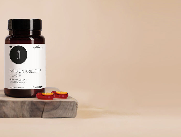 Die Produktdose von Nobilin Krillöl® Forte – Krillöl-Kapseln von Medicom – und zwei Licaps-Kapseln im Vordergund auf einem Holztablett