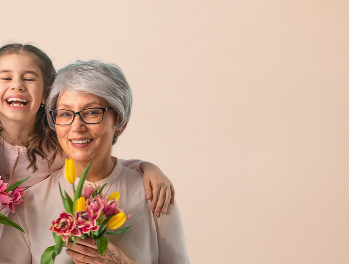 Bild zum Muttertag. Drei Generationen, Oma, Mutter und Kind. Oma und Mutter halten Tulpensträuße in der Hand.