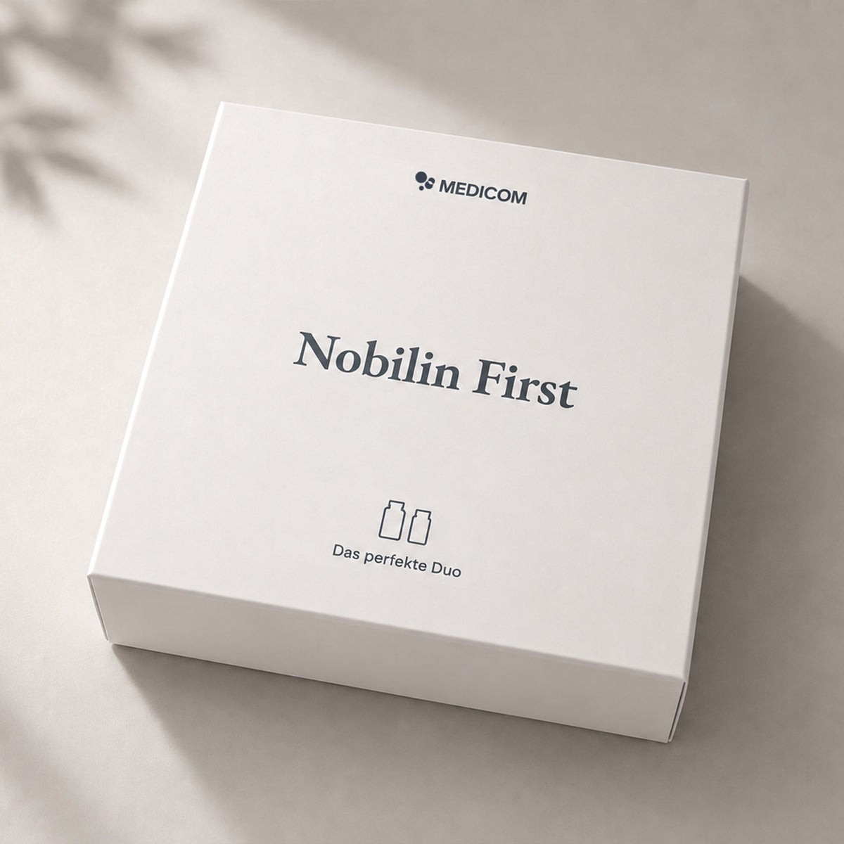 IDie neue, wiederwendbare Medicom-Box: Quadratische, weiße Nobilin First-Packung und einem Symbol, das zwei Produktdosen darstellt.