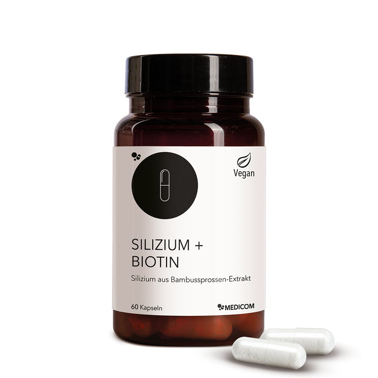 Die Produktdose von Silizium + Biotin in der Vorderansicht und zwei Kapseln vor der Produktdose