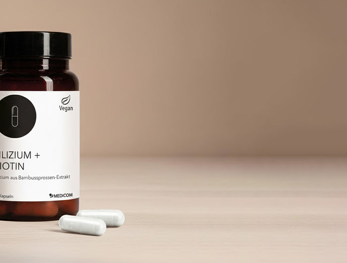 Die Produktdose von Silizium + Biotin und zwei Kapseln im Vordergrund