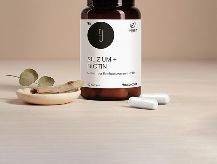 Das Produkt Silizium + Biotin von Medicom mit zwei Kapseln vor der Produktdose