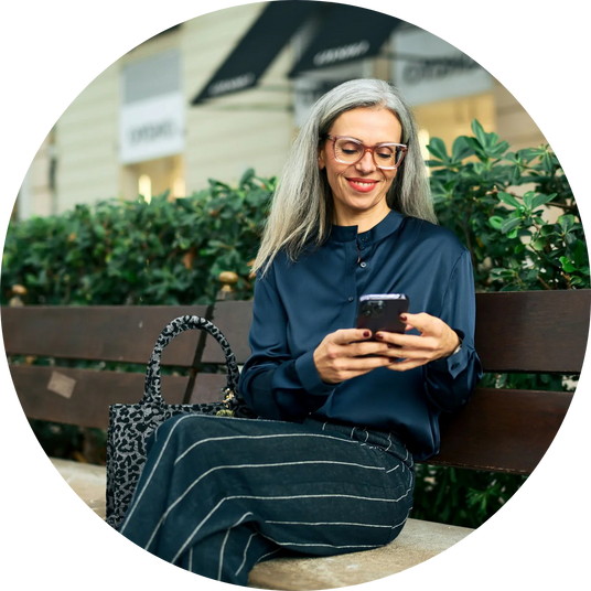 Die Geschäftsführerin von Medicom Ana Lorena Gomez sitzt auf einer Bank und schaut lächelnd auf ihr Smartphone